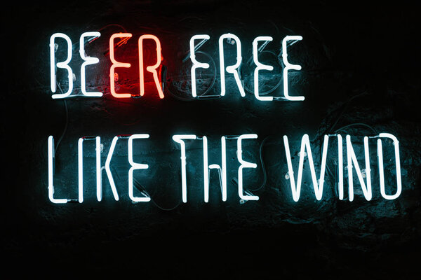 beer free like the wind neon inscription on dark wall in bar
