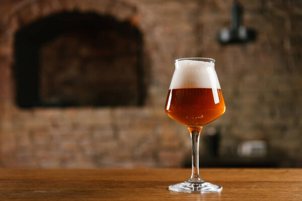 close-up view of fresh cold beer in glass on wooden table in bar