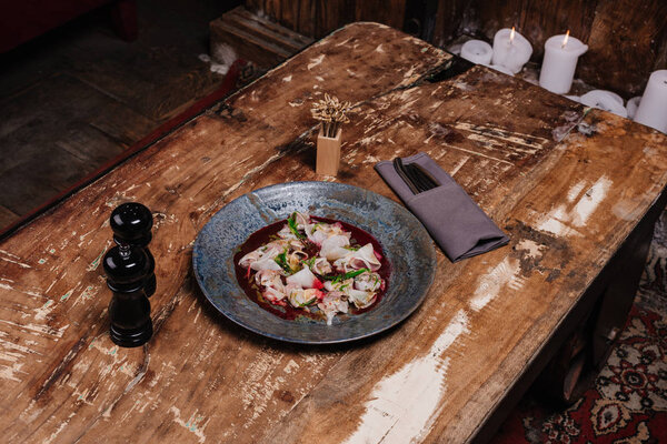high angle view of fresh tasty Ceviche with dorado and daikon on wooden table in restaurant