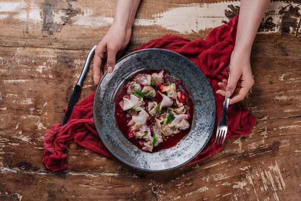 cropped shot of human hands and delicious ceviche with dorado in plate