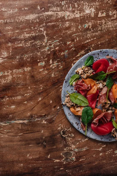top view of fresh gourmet salad with mussels, vegetables and jamon on wooden table 