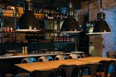 dřevěné stoly, lampy a bar pult v moderní restauraci