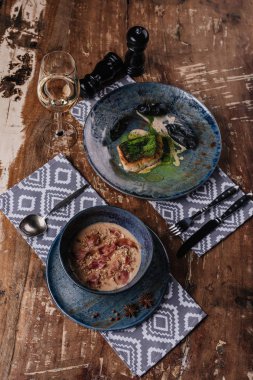 close-up view of delicious cream soup and fried zander on wooden table clipart