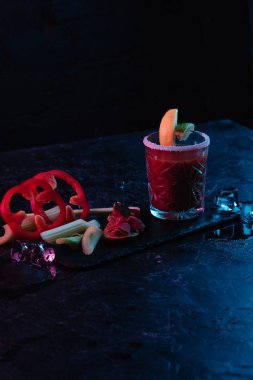 Bloody mary kokteyl cam ve buz küpleri karanlık yüzeyinde Ergitme ile sebze 