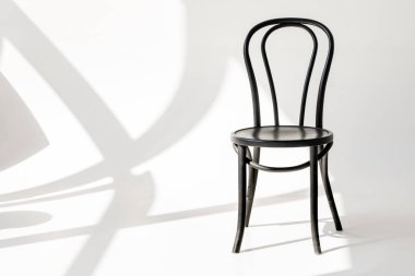 close up view of black wooden chair on grey backdrop with shadows