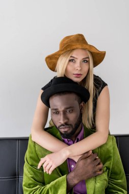 Kafkas kadın kucaklama şık Afro-Amerikan erkek gri izole Divan