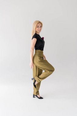 Tam boy görünüm kameraya gülümseyen ve gri poz şık genç kadın 