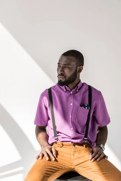 Porträtt Fundersam Afroamerikanska Man Snygga Kläder Sitter Stol Grå Bakgrund — Gratis stockfoto