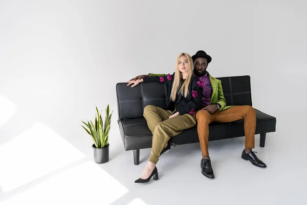 Multicultural Casal Elegante Descansando Sofá Preto Fundo Cinza — Fotografia de Stock