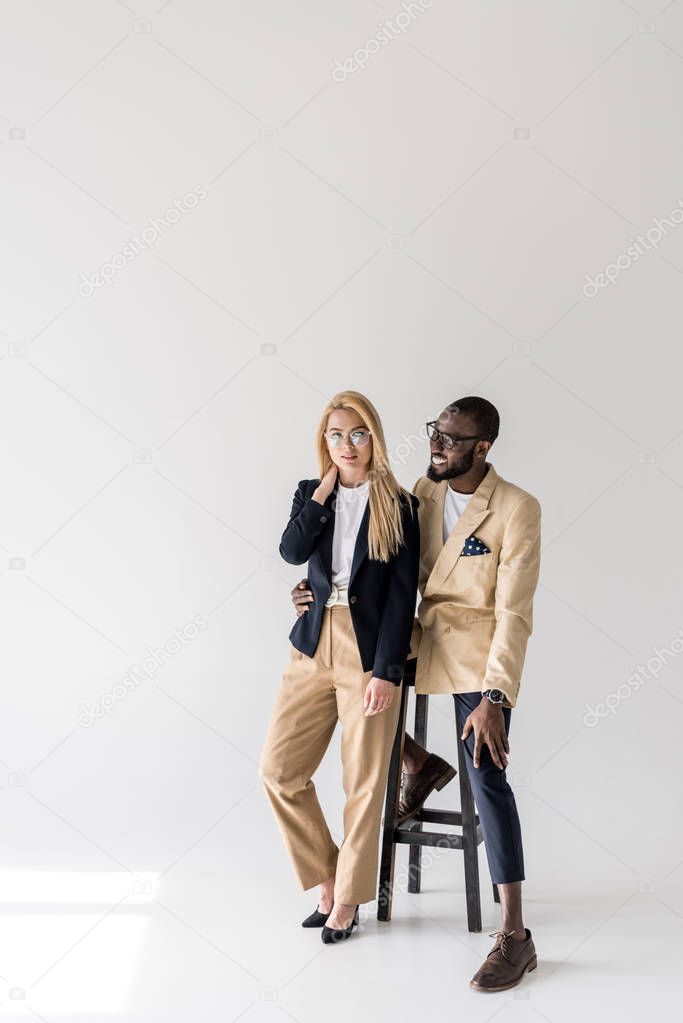 beautiful fashionable young multiethnic couple in spectacles posing together on grey