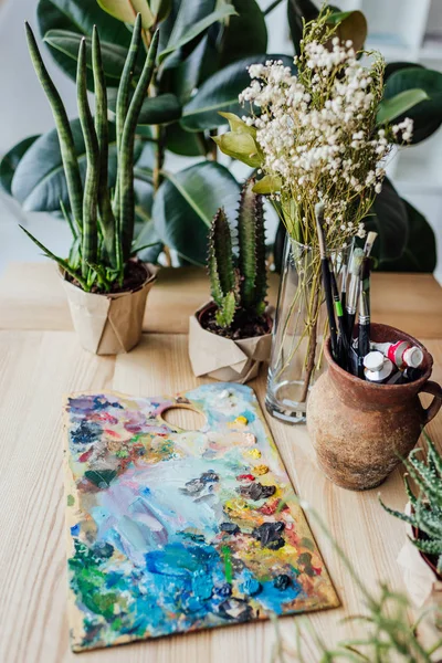 Plantas verdes con suministros de arte en la mesa - foto de stock