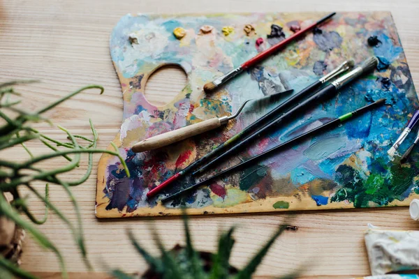 Palette of artist with paint brushes — Stock Photo