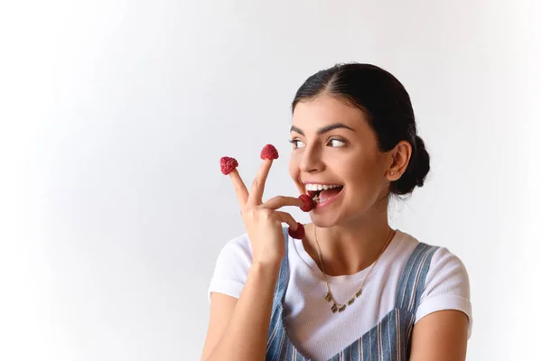 Woman with raspberries on fingers — Stock Photo