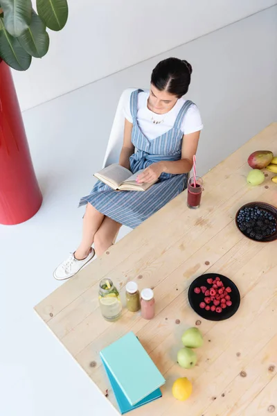 Donna che legge libro a tavola — Foto stock