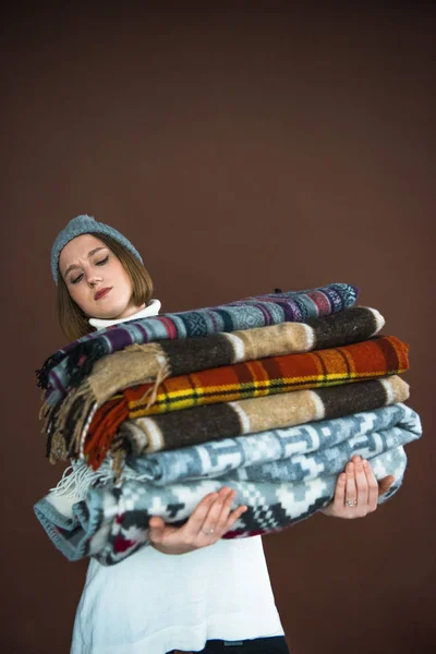 Woman holding heavy pile of blankets — Stock Photo