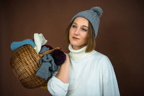 Femme tenant panier avec chapeaux et écharpes — Photo de stock