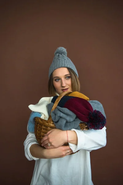 Mulher segurando cesta com chapéus e lenços — Fotografia de Stock