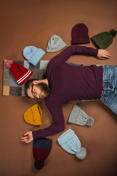 Homme couché parmi les chapeaux d'hiver — Photo de stock