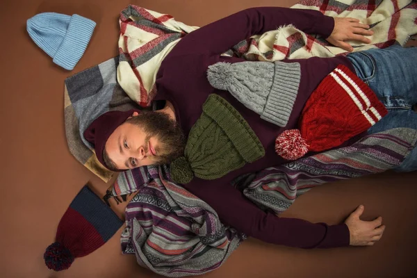 Man lying between scattered hats — Stock Photo