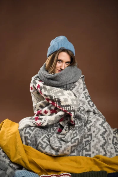 Femme assise enveloppée dans des couvertures — Photo de stock