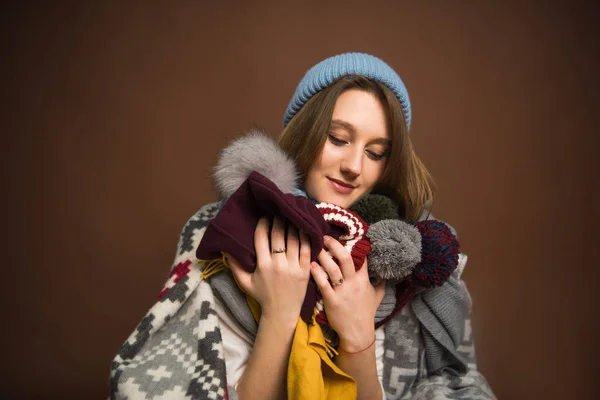 Chica sosteniendo sombreros de invierno - foto de stock