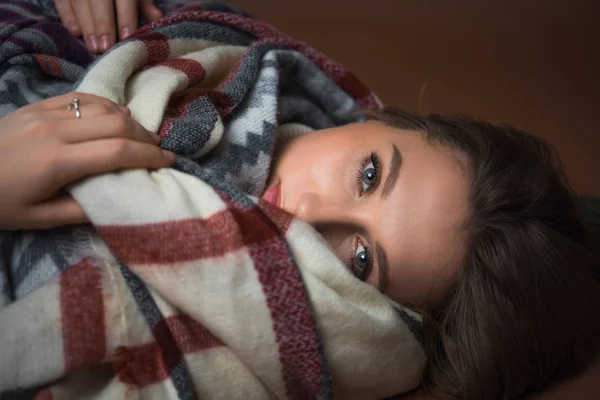 Donna sdraiata sul pavimento avvolta in una coperta — Foto stock
