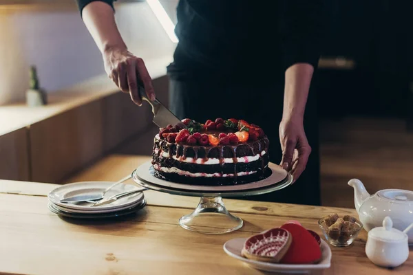 Femme coupe gâteau au chocolat — Photo de stock