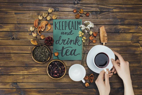 Hands with tea cup and card — Stock Photo