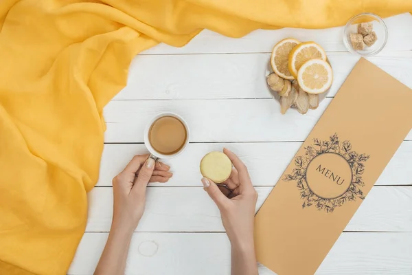 Xícara de chá e macaron nas mãos — Fotografia de Stock