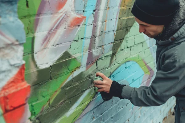 Artista callejero pintando graffiti colorido en la pared - foto de stock