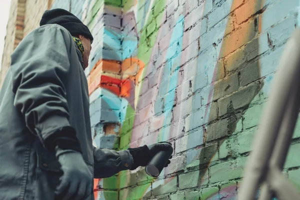 Уличный художник рисует красочные граффити на стене — стоковое фото