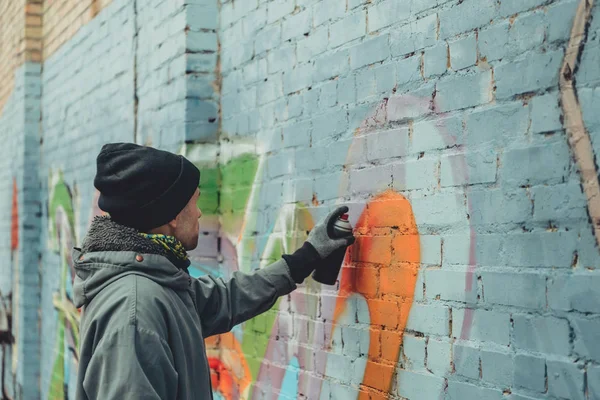 Artista callejero masculino pintando graffiti colorido en la pared - foto de stock