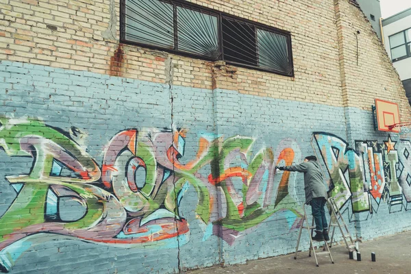 Tiefschnitt-Ansicht von Mann, der bunte Graffiti auf Gebäude malt — Stockfoto