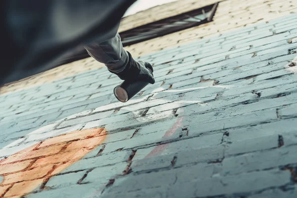 Vue du bas de l'homme peinture graffiti coloré sur le mur — Photo de stock