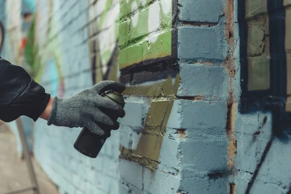 Vista recortada del hombre pintando graffiti colorido en la pared - foto de stock