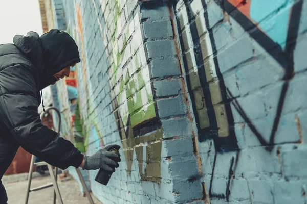 Artista callejero pintando graffiti colorido en la pared - foto de stock