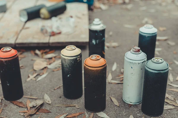 Cans with colorful spray paint for graffiti on asphalt — Stock Photo