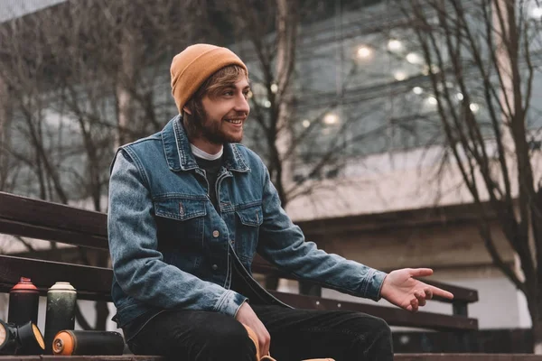 Male street artist sitting near cans with spray paint — Stock Photo