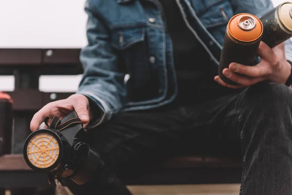 Cropped view of street artist holding cans with colorful spray paint — Stock Photo