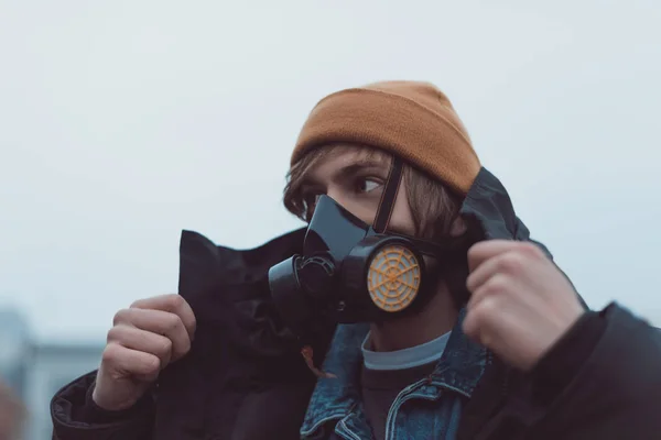 Portrait of young man in respirator and hat — Stock Photo