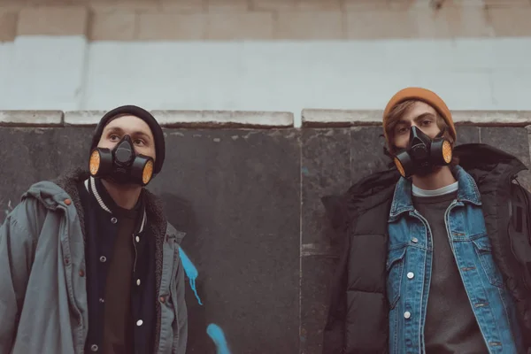 Street artists in respirators standing at wall — Stock Photo