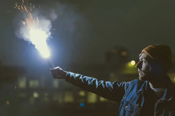 Mann hält in der Nacht Rauchbombe mit Funken in der Hand — Stockfoto