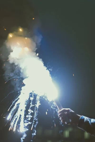 Ausgeschnittene Ansicht einer männlichen Hand mit Rauchbombe mit Funken in der Nacht — Stockfoto