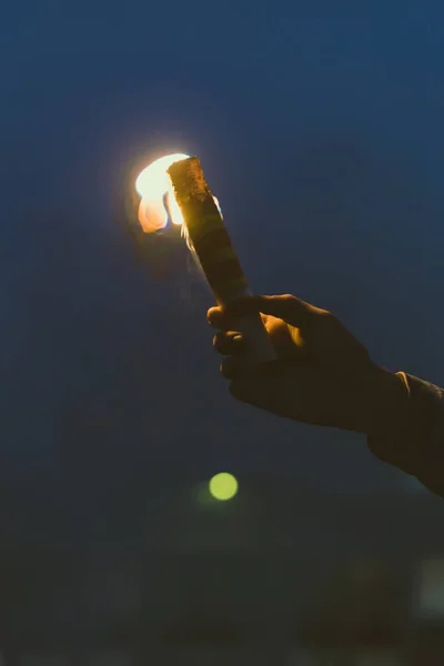 Ausgeschnittene Ansicht der männlichen Hand mit Rauchbombe mit Feuer in der Nacht — Stockfoto