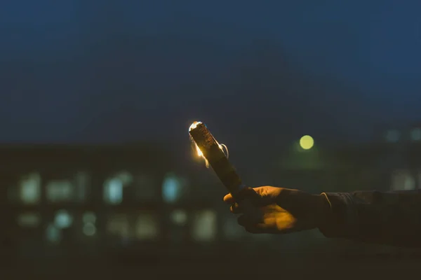 Cropped view of male hand with smoke bomb with fire at night — Stock Photo