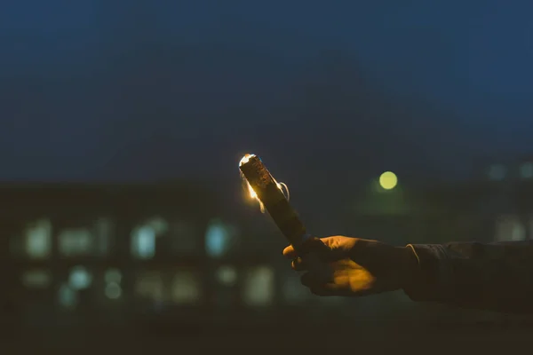 Vue recadrée de la main masculine avec bombe fumigène avec feu la nuit — Photo de stock