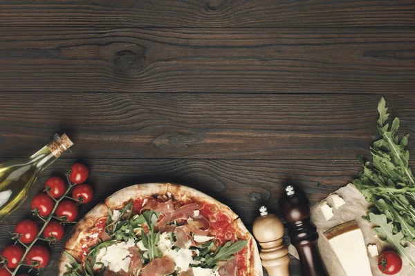 Flat lay with italian pizza and various ingredients on wooden tabletop — Stock Photo