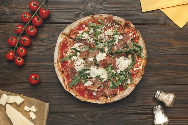 Tumbado plano con pizza italiana casera, aceite de oliva, tomates cherry y queso en la superficie de madera - foto de stock