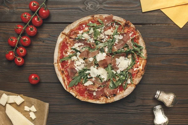 Flat lay with homemade italian pizza, olive oil, cherry tomatoes and cheese on wooden surface — Stock Photo