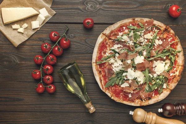 Flat lay with homemade italian pizza, olive oil, cherry tomatoes and cheese on wooden surface — Stock Photo